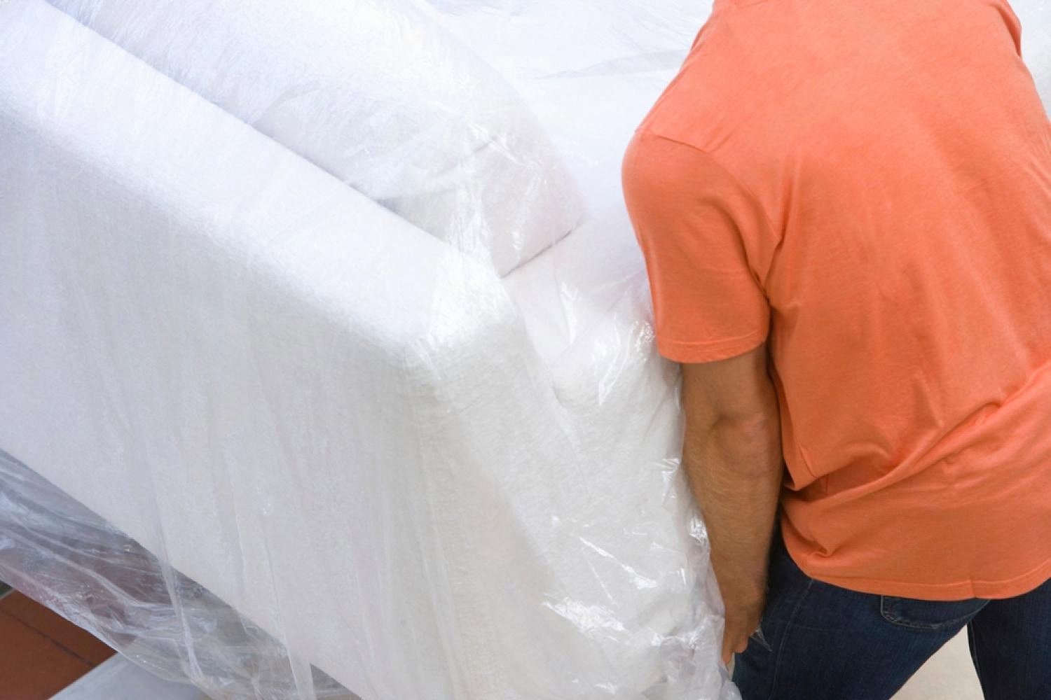 Person carrying a wrapped sofa, illustrating furniture delivery for a UAE rental