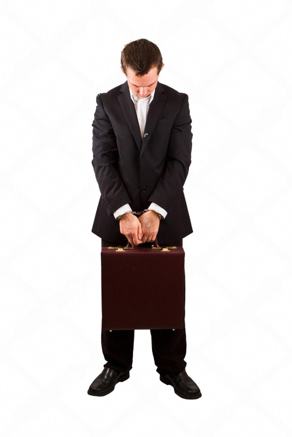Man in a business suit with handcuffs holding a briefcase, symbolising internal corporate fraud